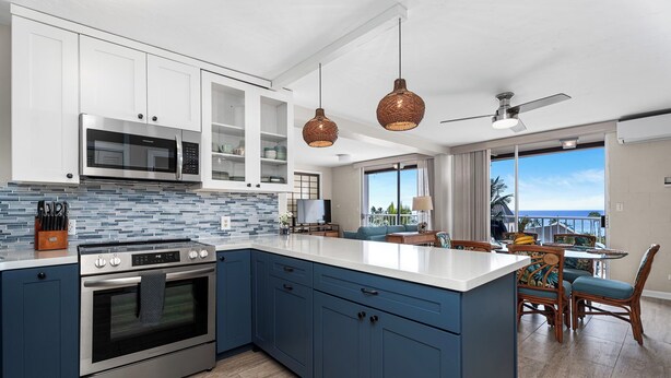 A modern kitchen with a large island, stainless steel appliances, and a view to the outside. - Kailua Village#705 Top Floor, Gorgeous Remodeled 2 bedroom, in Heart of Town (Kailua Kona)