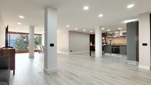 A spacious living area with a large window, a kitchen, and a seating area.