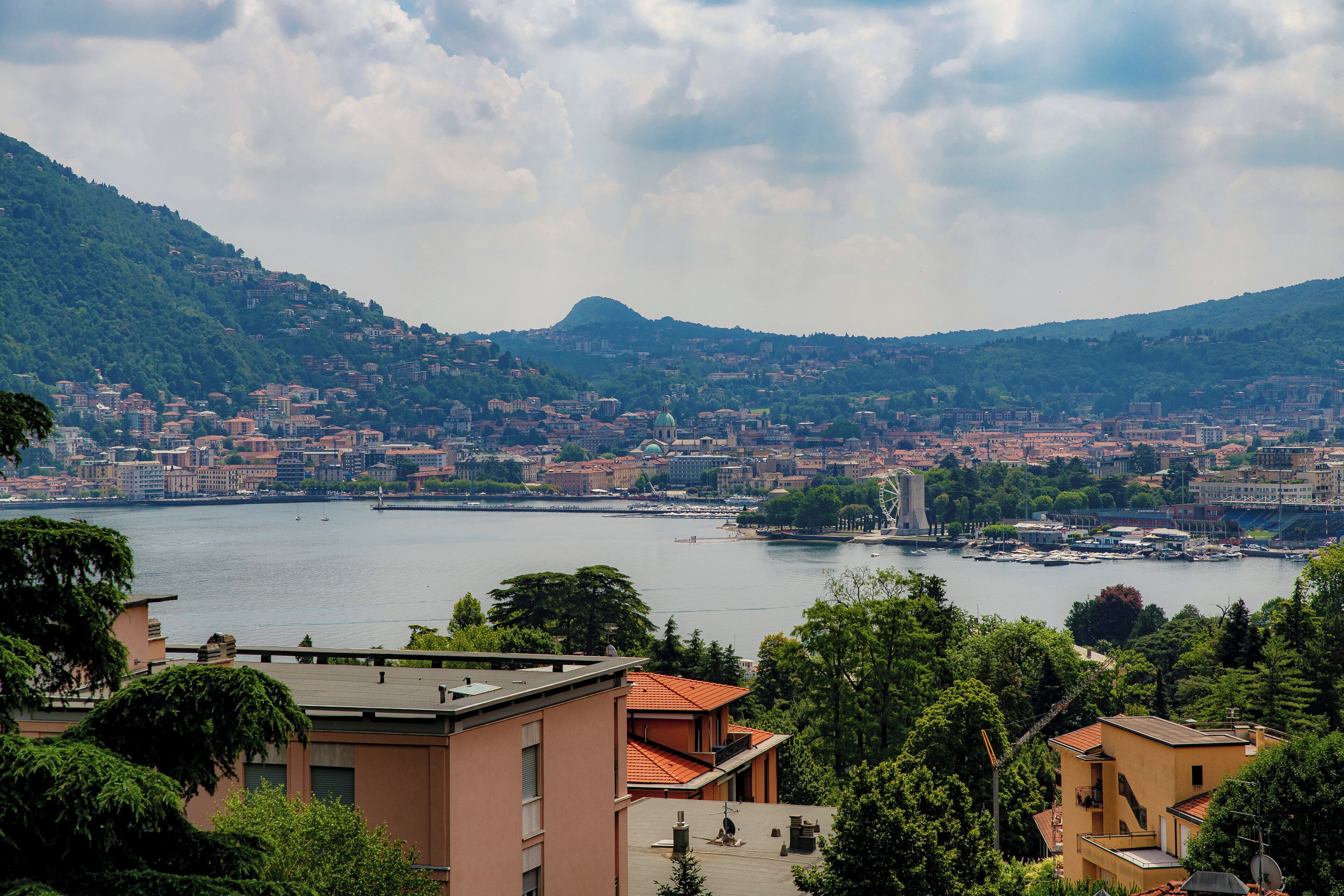 A panoramic view of a city with a river, buildings, and hills.