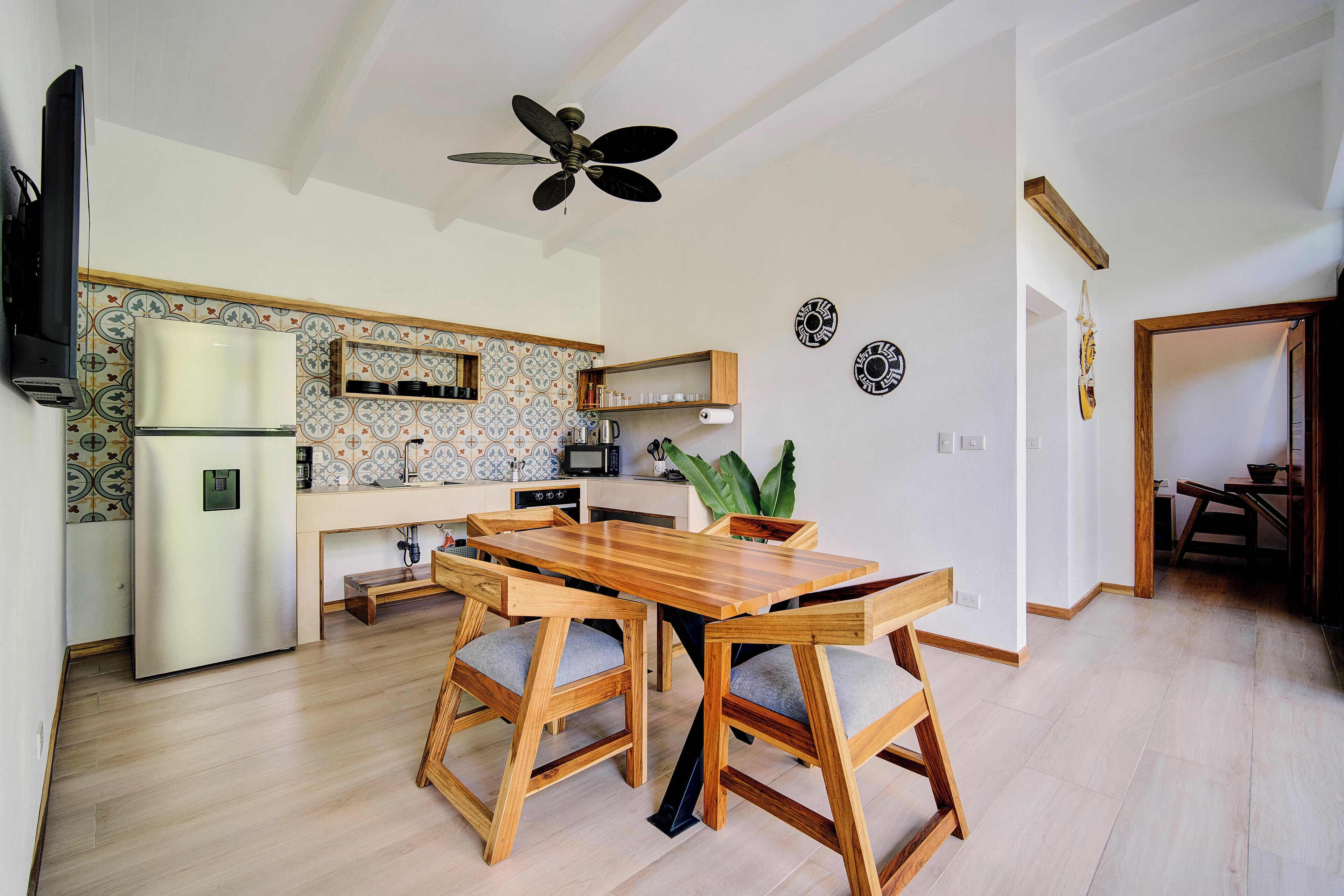 Una cocina moderna con una mesa y sillas de madera, un refrigerador empotrado y un ventilador de techo.