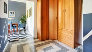A hallway with a checkered floor, a wooden wardrobe, a dining table with chairs, and framed artwork on the walls. - JOIVY Stylish Flat in Porta Genova (Milan)