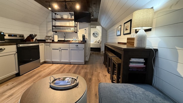 Een moderne keuken met houten kastjes, een inbouwoven en een eethoek met een bankje en tafel.