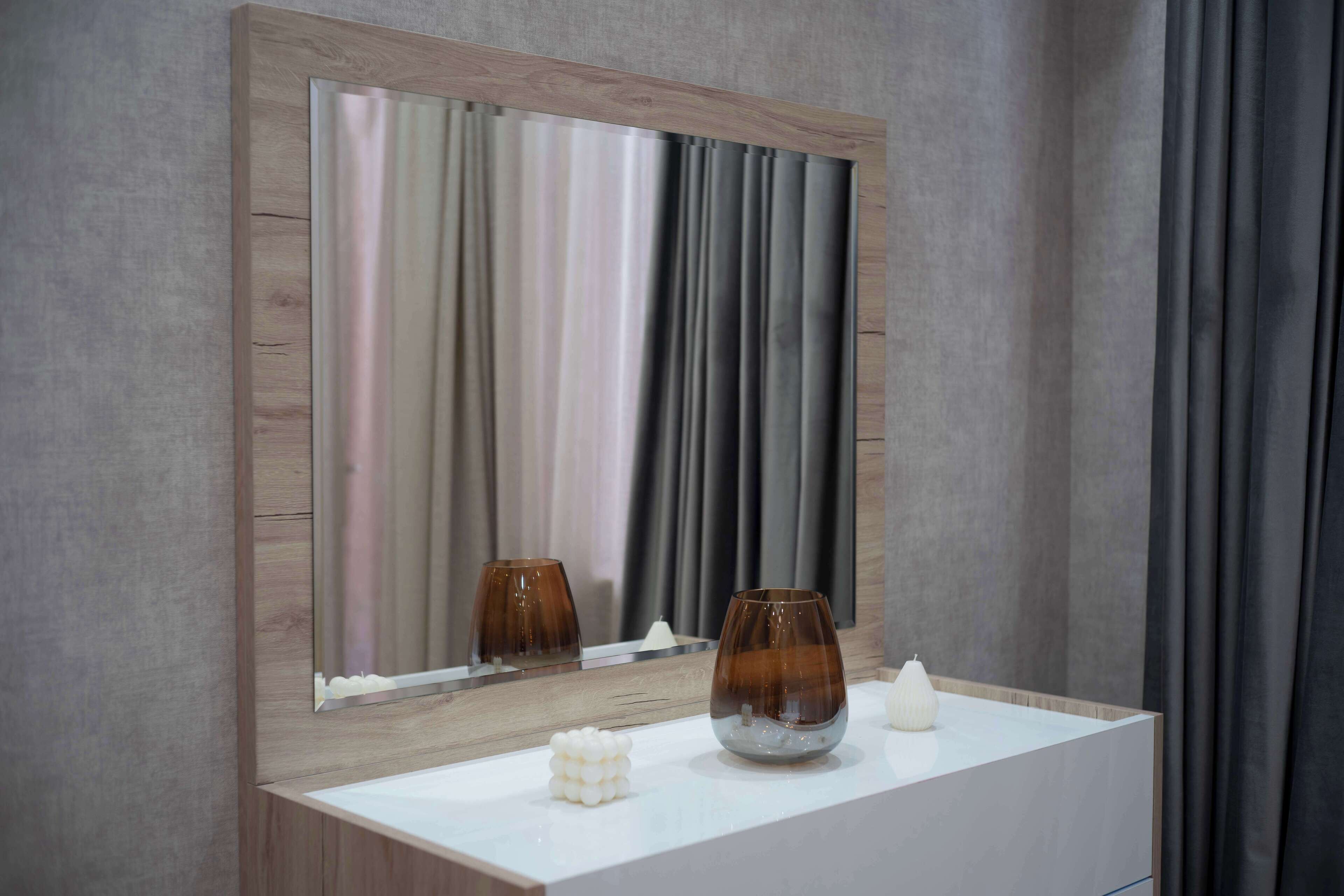 A bathroom with a wooden vanity, a mirror, and two candles on the counter.