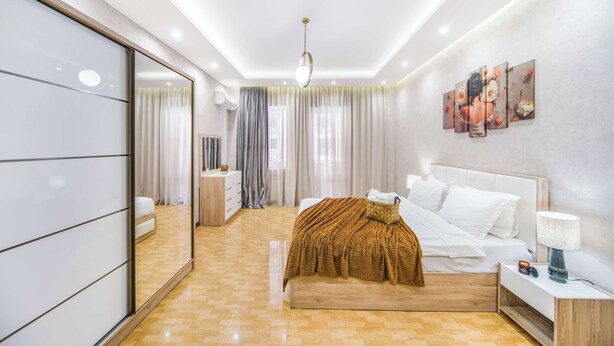 A modern bedroom with a large bed, bedside table, and a mirror. - Stay Inn on North 11 (Yerevan)