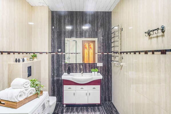 A modern bathroom with a vanity, sink, and towel rack.