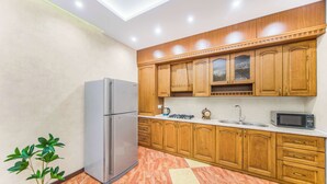 A kitchen with wooden cabinets, a stainless steel refrigerator, a microwave, and a sink. - Stay Inn on North 11 (Yerevan)