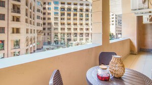 A balcony with a view of high-rise buildings, a round table with a cushion, and a wicker basket. - Stay Inn on North 11 (Yerevan)