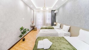 A modern hotel room with two beds, a potted plant, a vanity with a mirror, and a ceiling light. - Stay Inn on North 11 (Yerevan)