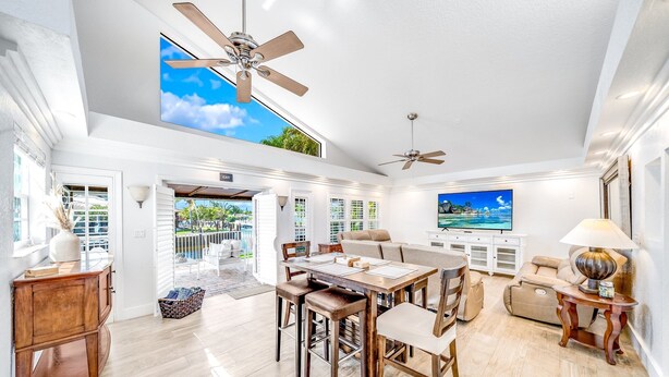 A spacious living area with a high ceiling, ceiling fans, a dining table with chairs, a sofa, and a TV. - Heated Pool! Waterfront+Kayak! Close 2 Beach! (Pompano Beach)