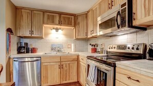 A kitchen with wooden cabinets, a stainless steel dishwasher, an oven, and a microwave.