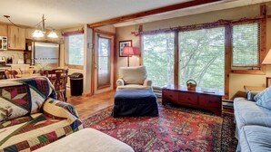 A cozy living room with a fireplace, a dining area, and a kitchen.