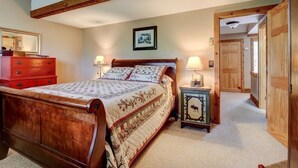 A bedroom with a wooden bed, two bedside tables with lamps, a red dresser, and a framed picture on the wall.