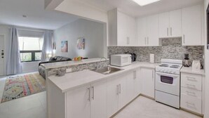 A modern kitchen with white cabinets, a microwave, a stove, and a sink. - Modern condo: Steps from Atlantis & Beach (Bayview Lane)