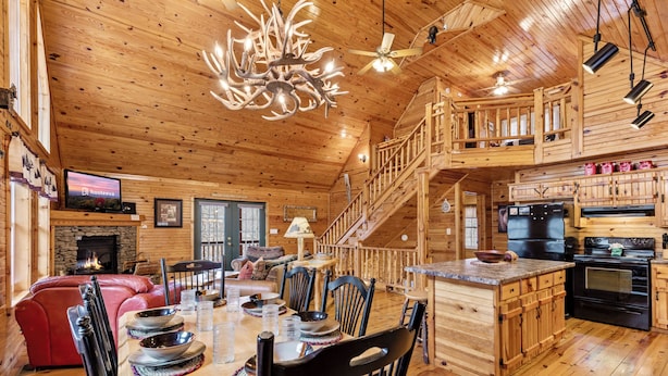 A wooden cabin interior with a dining area, kitchen, and a fireplace. - Hickory Hollow Hideaway (Sevierville)