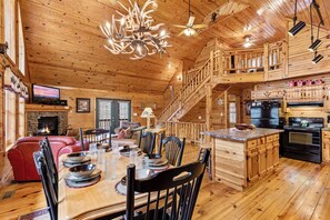 A wooden cabin interior with a dining area, kitchen, and a fireplace. - Hickory Hollow Hideaway (Sevierville)