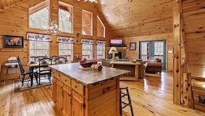 A spacious wooden cabin with a large kitchen area, dining table, and seating. - Hickory Hollow Hideaway (Sevierville)