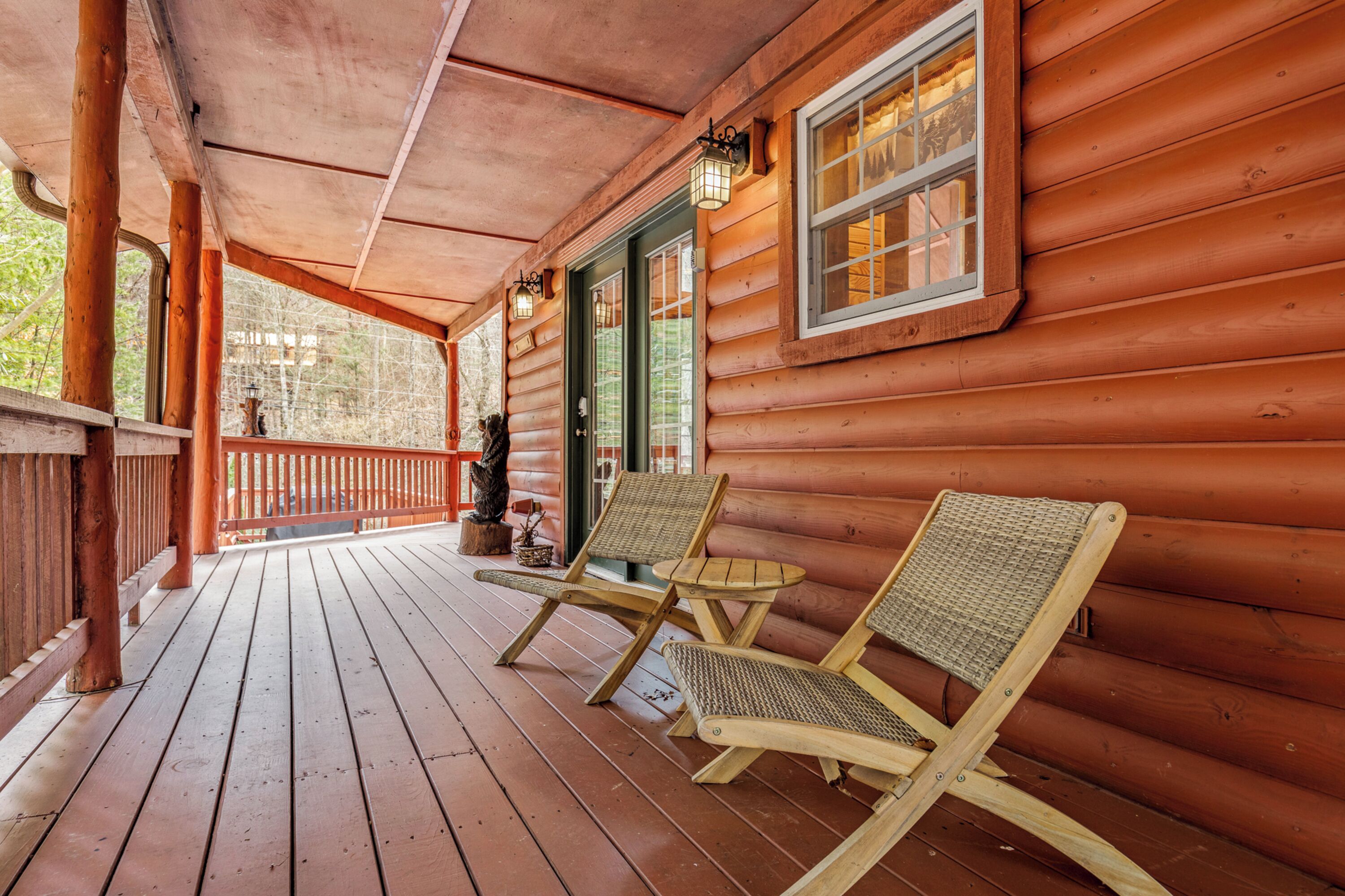 Une cabane en bois avec une véranda, deux fauteuils en osier et une petite table.