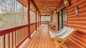 A wooden porch with a bench and a hammock, overlooking a forested area. - Hickory Hollow Hideaway (Sevierville)