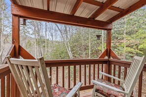 A wooden deck with two chairs and a covered area. - Hickory Hollow Hideaway (Sevierville)