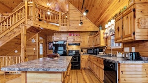 A wooden cabin-style kitchen with granite countertops, a central island, a stove, and a dishwasher. - Hickory Hollow Hideaway (Sevierville)
