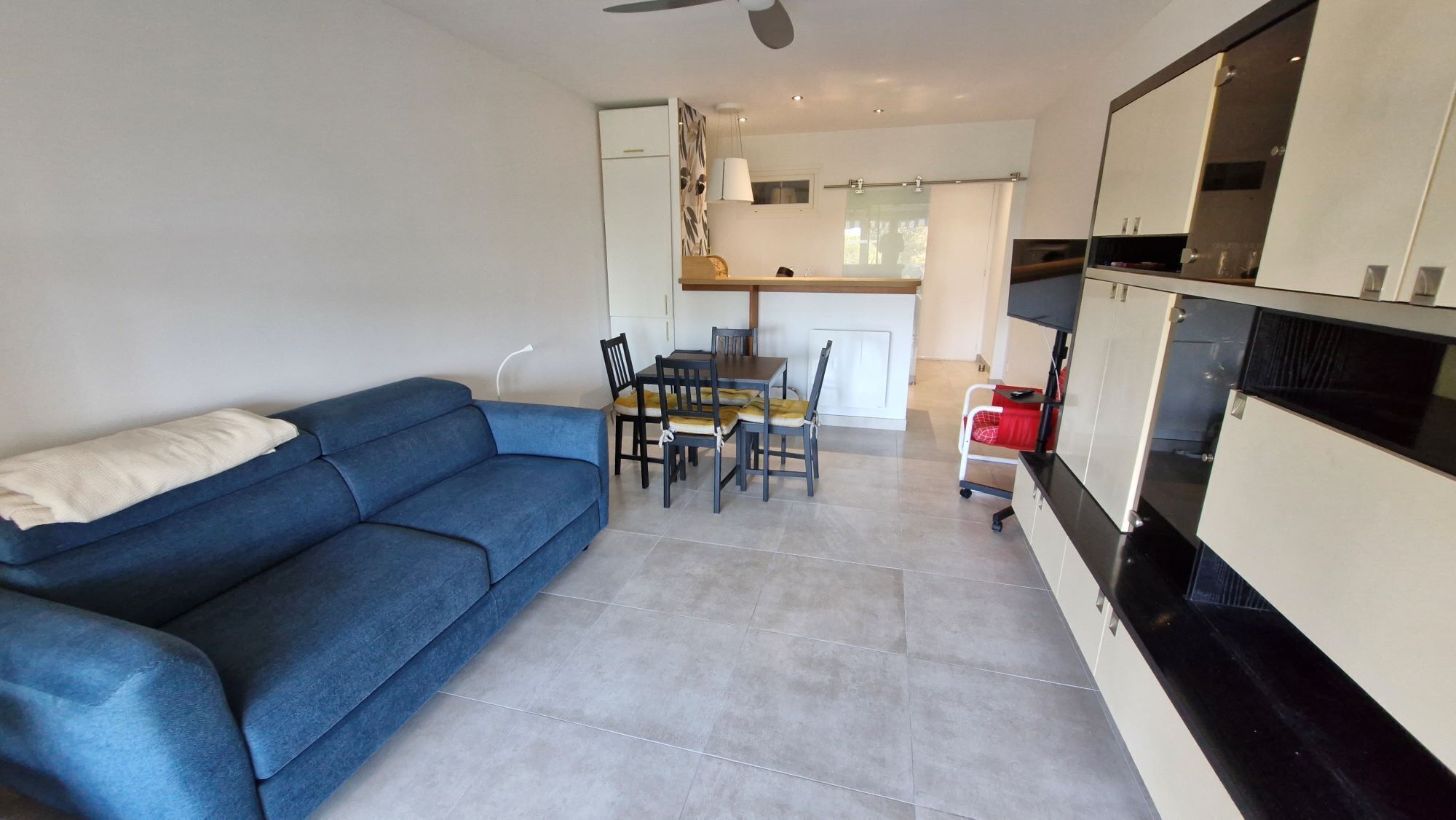 A compact living space with a sofa, dining table, chairs, and a kitchenette.