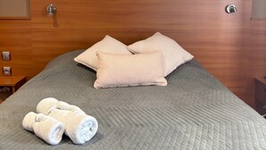 A neatly made bed with a grey quilt, two striped pillows, and rolled white towels. - Chez Anabel & Stéphane (Battenheim)