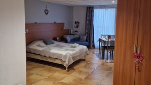 A hotel room with a bed, a smaller bed, a wardrobe, a desk, and a chair. - Chez Anabel & Stéphane (Battenheim)