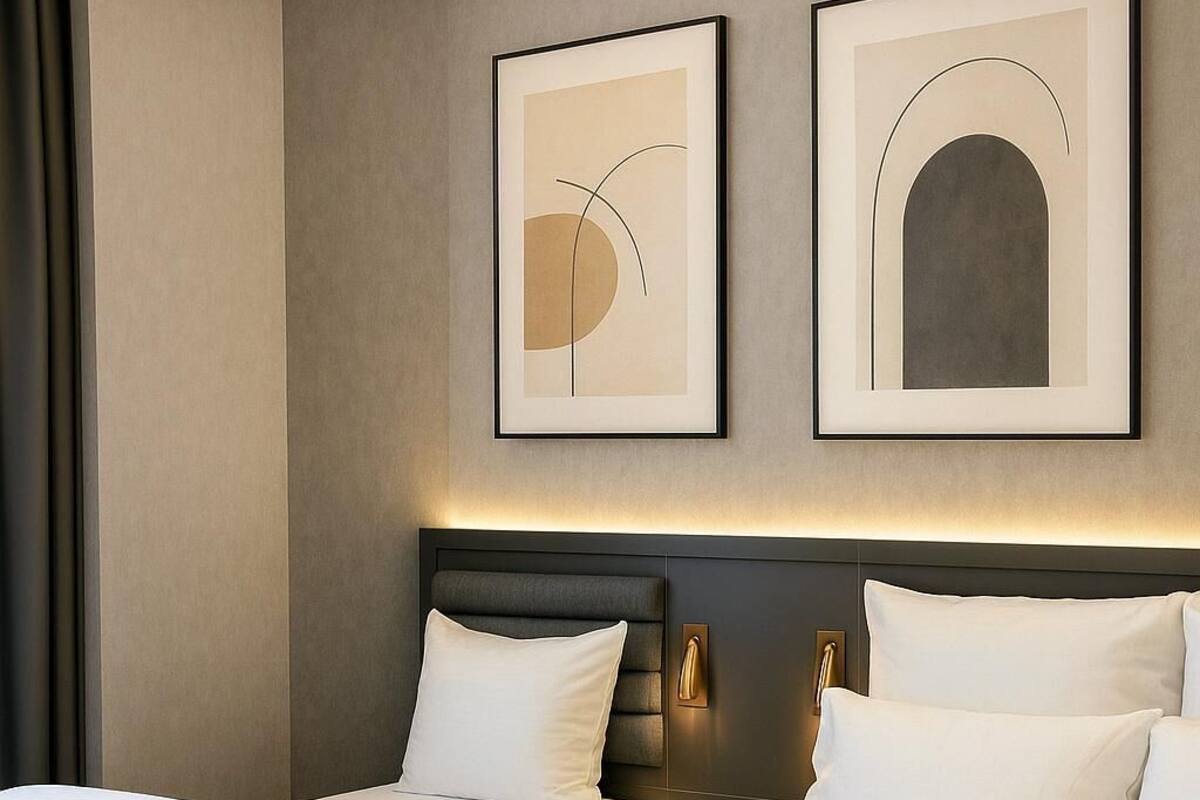 A hotel room with two beds, a dark headboard, and two framed abstract artworks on the wall.