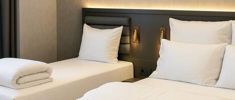 A hotel room with two beds, a dark headboard, and two framed abstract artworks on the wall.