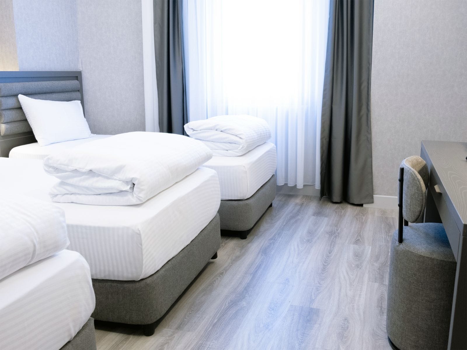 Habitación de hotel con dos camas, un escritorio y una ventana con cortinas.