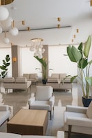 Uma área de estar moderna, com sofás, uma mesa de centro e luminárias esféricas penduradas.
