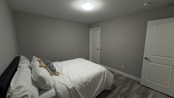 A bedroom with a bed, a door, and a ceiling light.