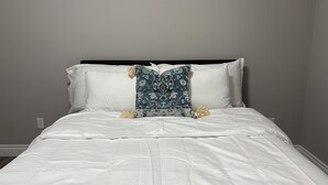 Un llit ben fet amb roba de llit blanca i una sola almoinada decorativa.