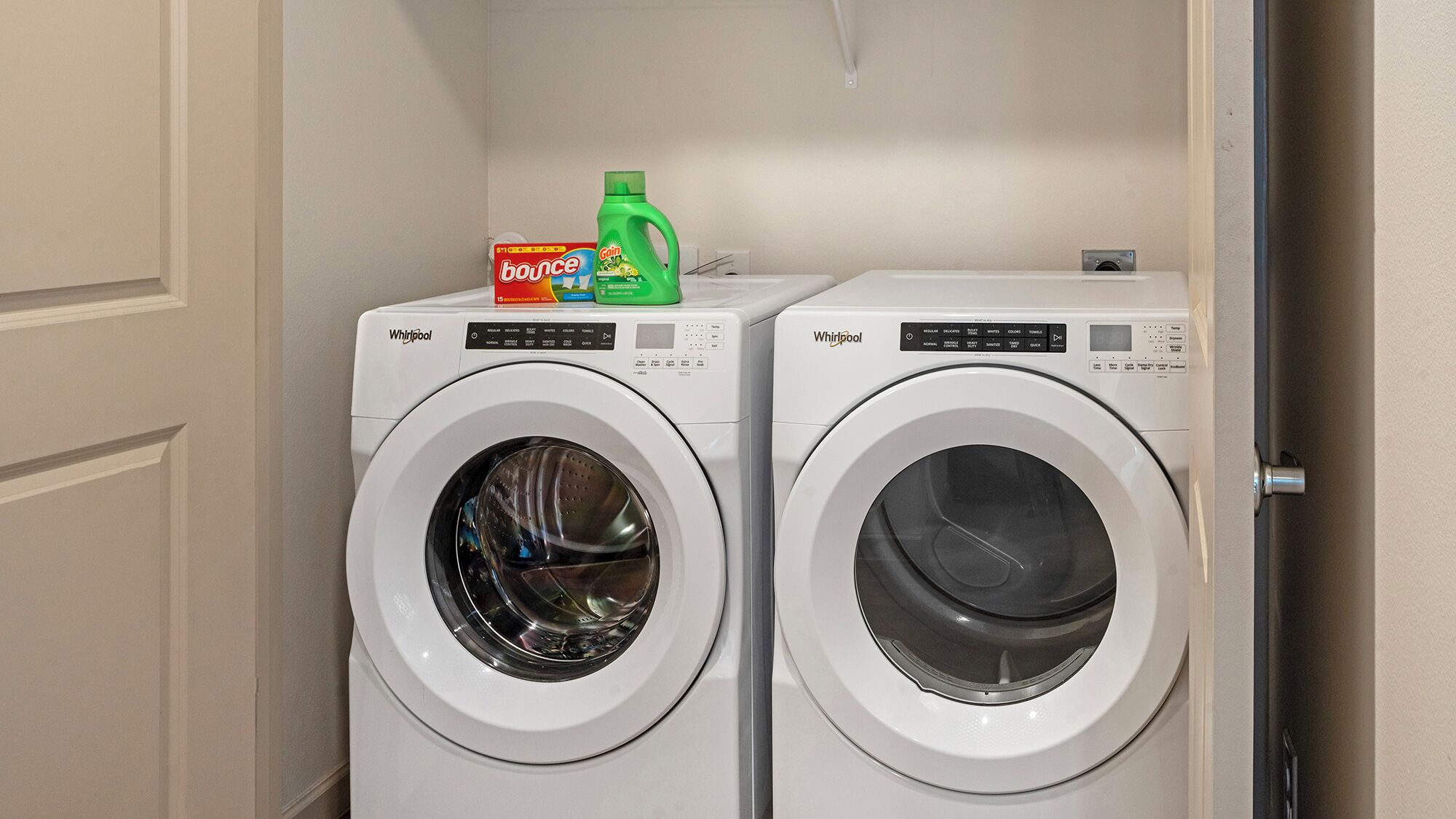 Dos lavadoras Whirlpool de carga frontal en un cuarto de lavado con una puerta a la derecha.