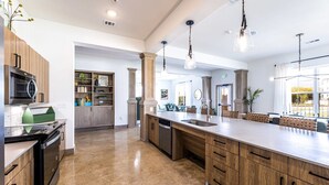 A modern kitchen with a large island, wooden cabinets, and pendant lighting. - Landing Apartments Pflugerville (Pflugerville)