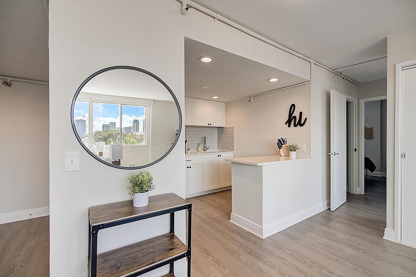 A modern kitchen with white cabinets, a central island, and a large mirror.