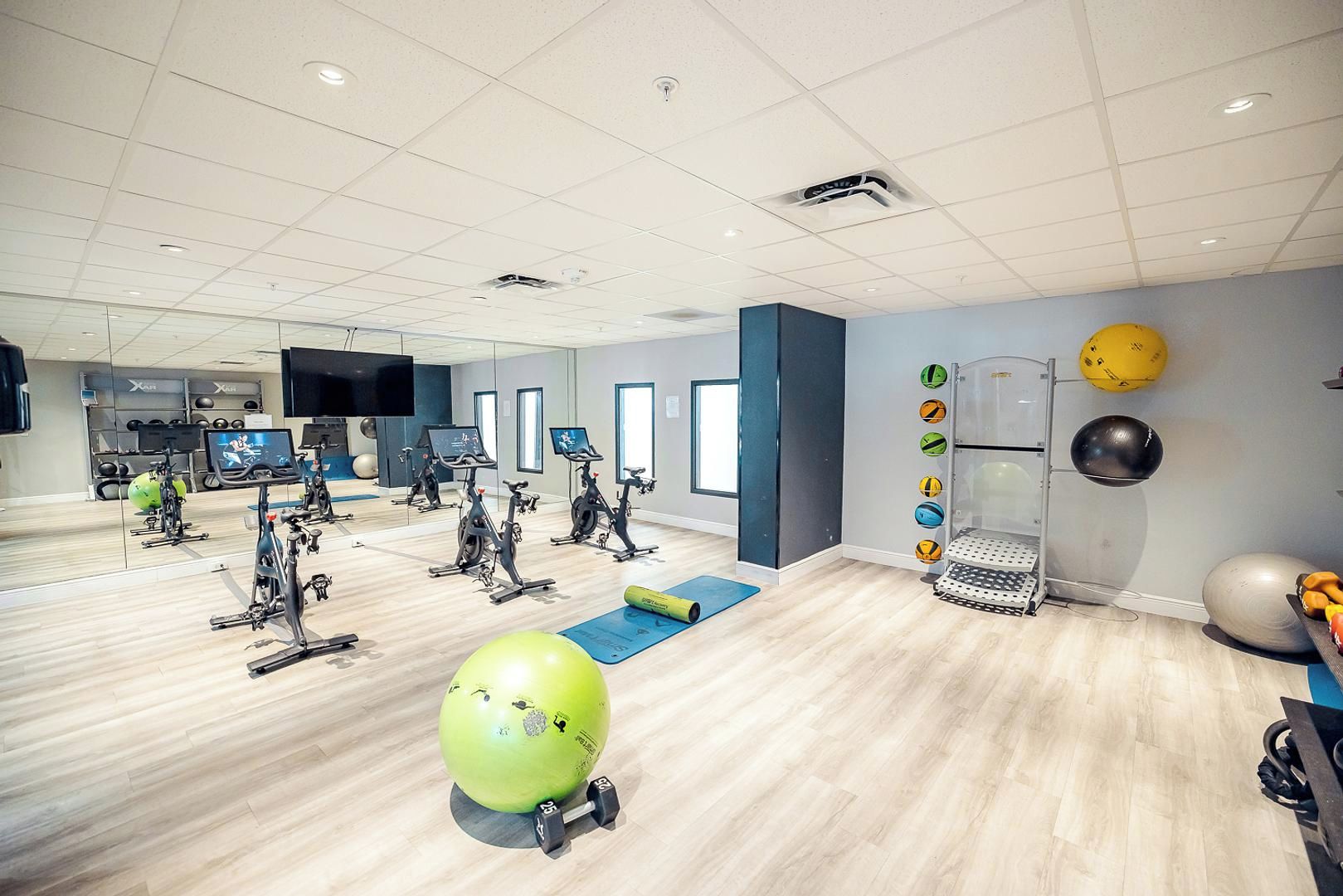 Ett gym med motionscyklar, en stor grön träningsboll och diverse annan träningsutrustning.