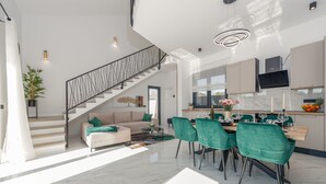 A spacious living area with a staircase, a dining area with green chairs, and a kitchen with a flat-screen TV. - Villa Dide moga ZadarVillas (Sveti Petar)