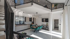 A spacious kitchen with modern appliances, a dining area with teal chairs, and a staircase with a black railing. - Villa Dide moga ZadarVillas (Sveti Petar)