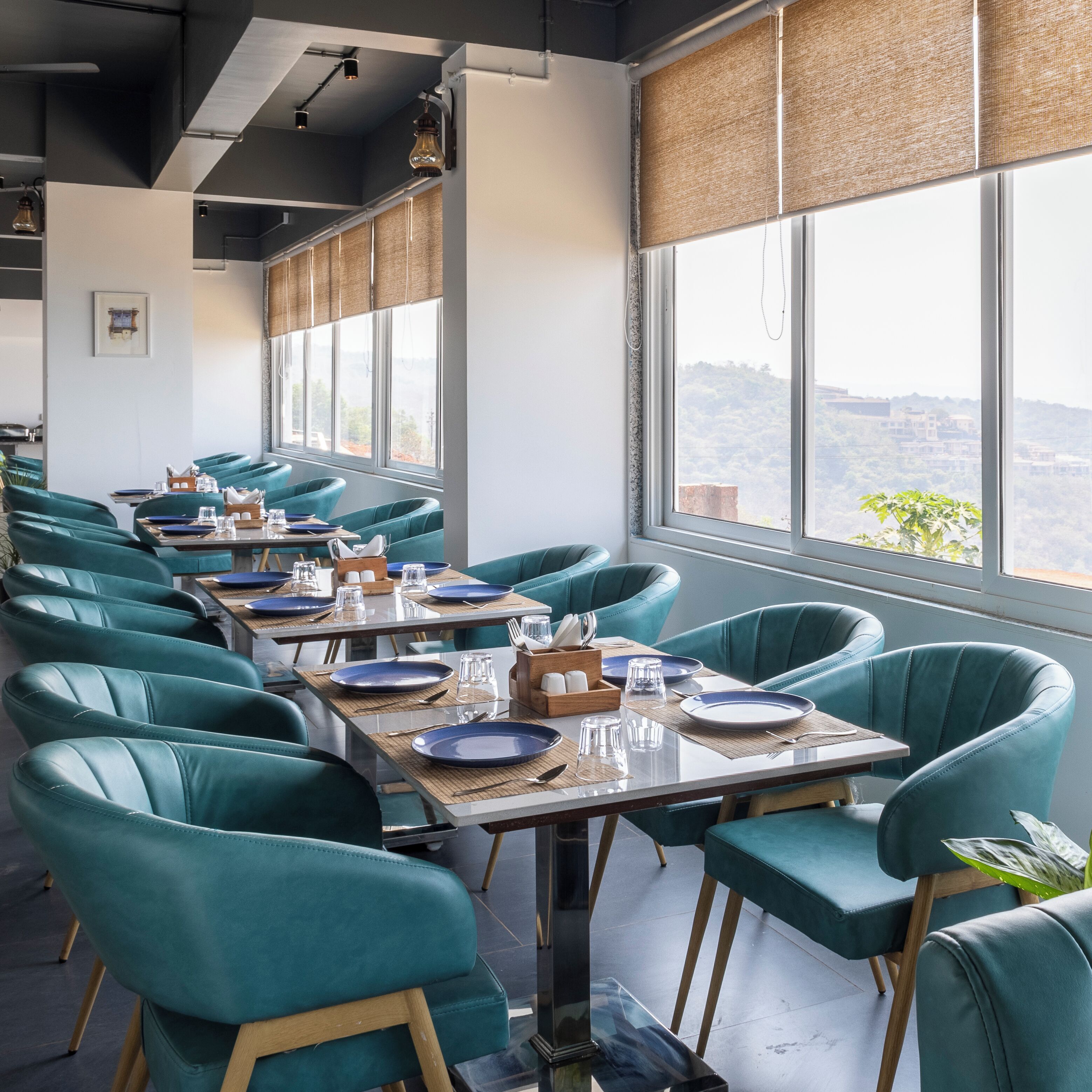 Zona pranzo con sedie e tavoli color acquamarina, ampie finestre con vista e un design d'interni moderno.
