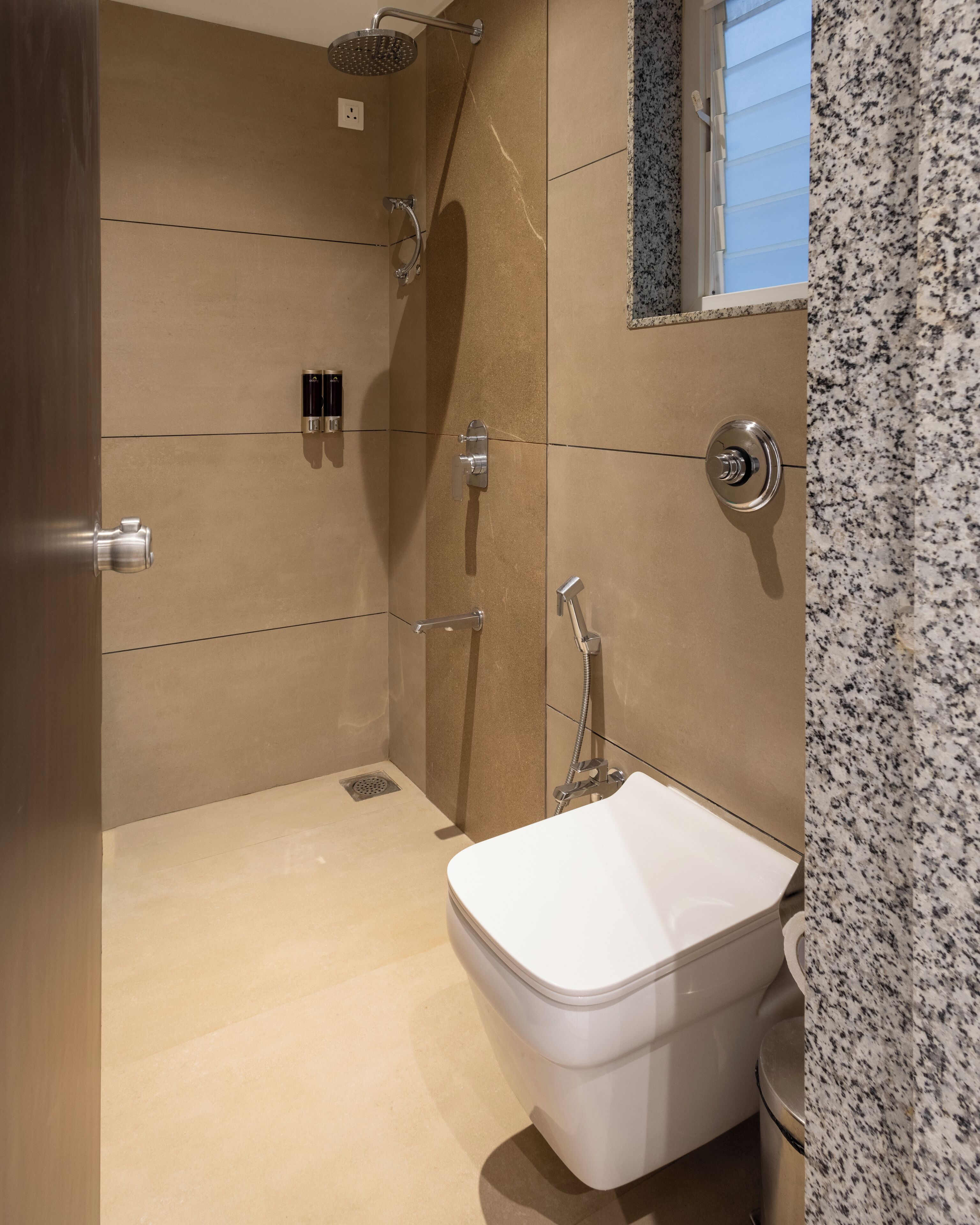 A modern bathroom with a walk-in shower, a toilet, and a window.