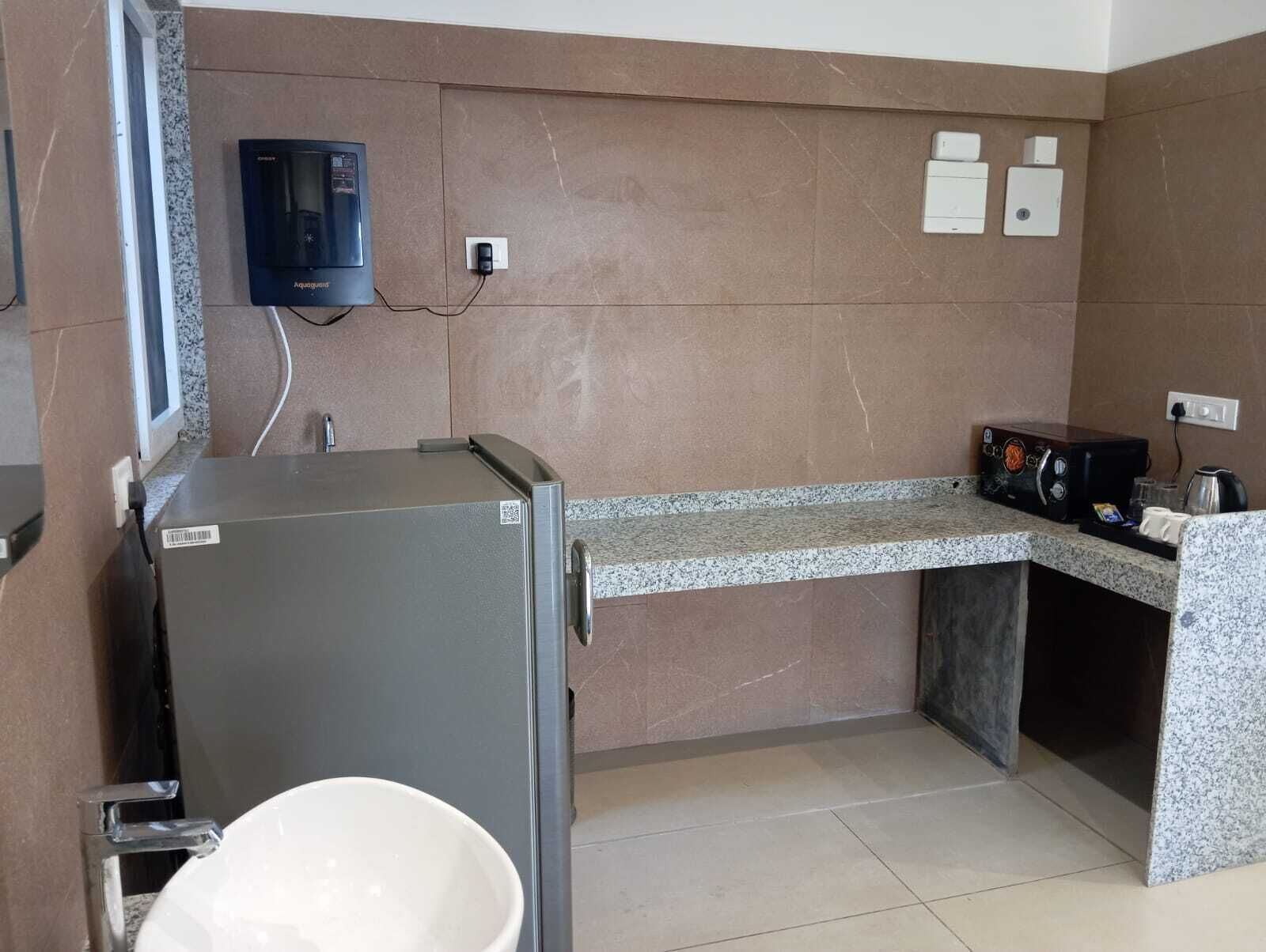Una cocina compacta con un refrigerador empotrado, un microondas y una cafetera en la encimera.