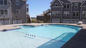 A swimming pool surrounded by residential buildings with multiple garages. - Modern Coastal Condo w/ Heated Pool Near Ogunquit & Wells Beach (Wells)