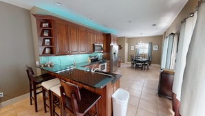 A kitchen with wooden cabinets, a central island, a microwave, and a refrigerator.