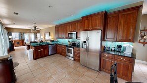 A spacious kitchen with wooden cabinets, a stainless steel refrigerator, a microwave, and a stove.