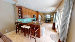A kitchen with wooden cabinets, a granite countertop, and a dining area with a chandelier.