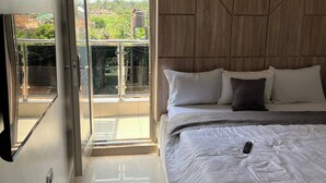 Een slaapkamer met een grote glazen schuifpui die uitkomt op een balkon.
