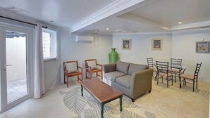 Uma sala de estar ampla com um sofá, duas poltronas, uma mesa de centro e um espaço de jantar com mesa e cadeiras.
