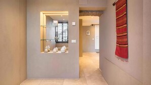 A hallway with a glass partition displaying decorative items, a red patterned curtain, and a glimpse of a room with a stone wall. - Ca' delle Contesse   Elegant 2BR apartment in Liberty villa   spectacular view! (Lido)