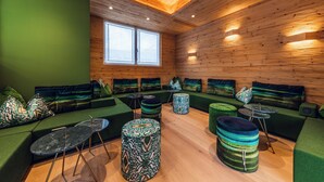 A modern interior with green sofas, patterned ottomans, and a wooden ceiling. - Loom Hotel (Bolzano)